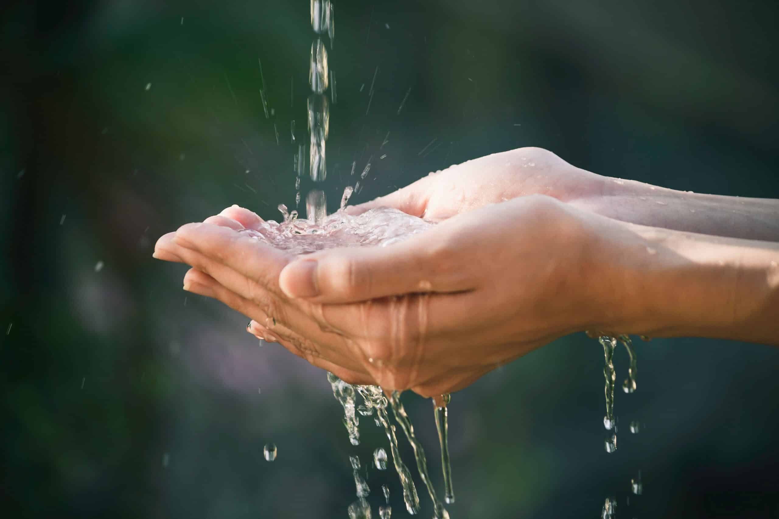 Eine Person hält ihre Hände unter einen Wasserstrahl