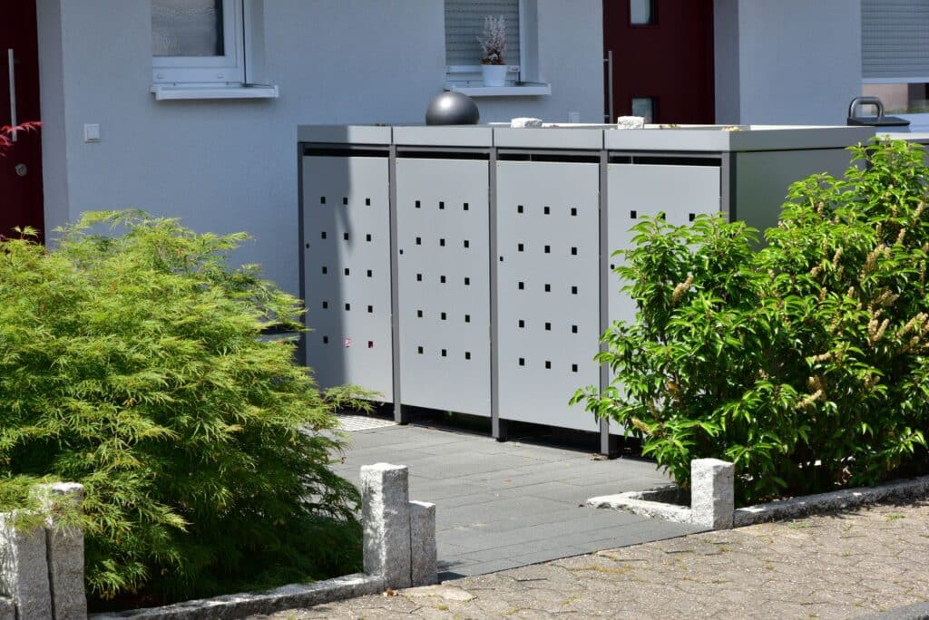 Moderne Mülltonnenverkleidung aus Metall im gepflegten Vorgarten eines Einfamilienhauses