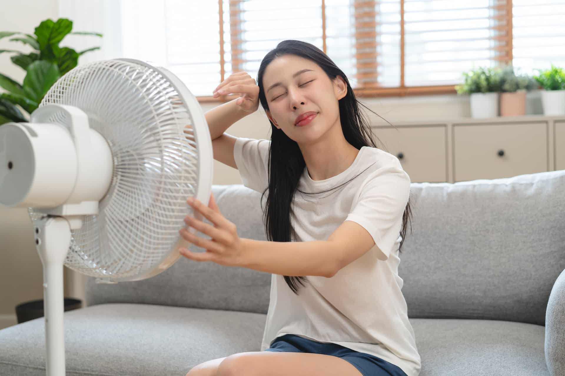 Frau kühlt sich mit Ventilator | Wandventilatoren
